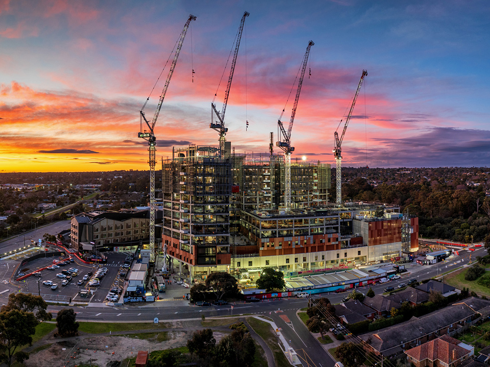 A view of the Frankston Hospital construction site at sunrise, with cranes visible across the site