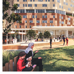 A young family relax on seats surrounded by grass with the hospital in the background