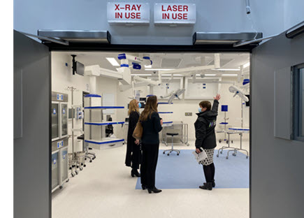 Photo of three Western Health clinicians standing inside an operating room prototype that contains medical equipment and fittings