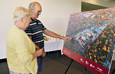 Two elderly people standing and looking at a large render for the redeveloped Frankston Hospital