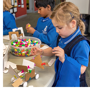 A young girl concentrates as she makes a cardboard model