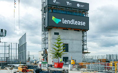 A tree on the top level of a construction site. The Lendlease logo is visible on a hoarding in the background