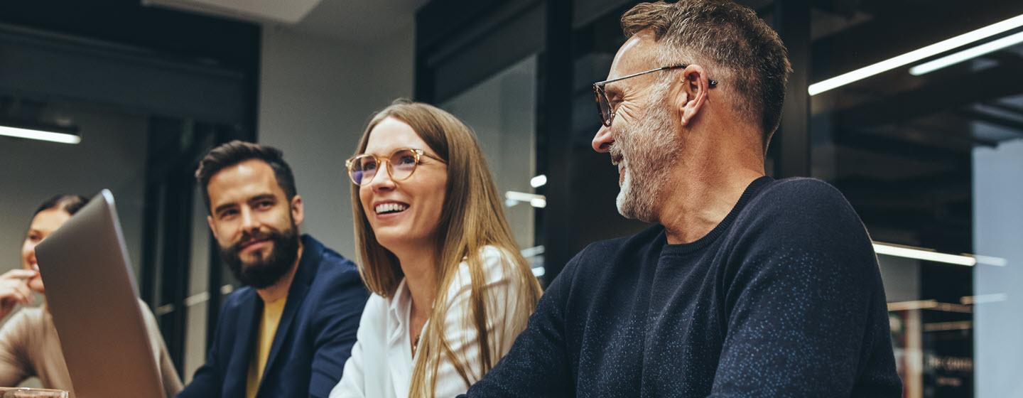 Image of two men and two women in a meeting room with laptops