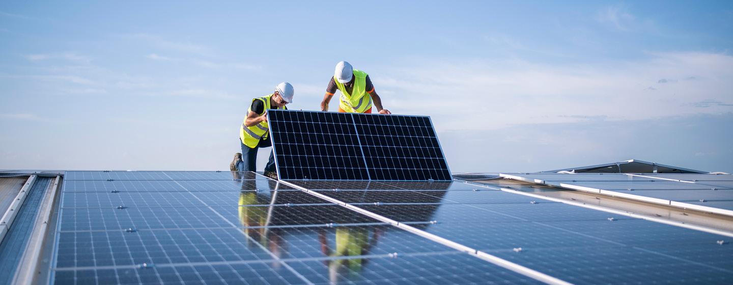 Two workers installing a solar panel on a roof