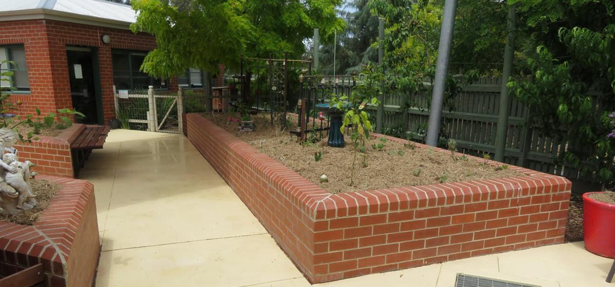 View of the paved garden space at Mountview Home at Maldon Hospital showing a flat walking path and accessible garden within an enclosed courtyard