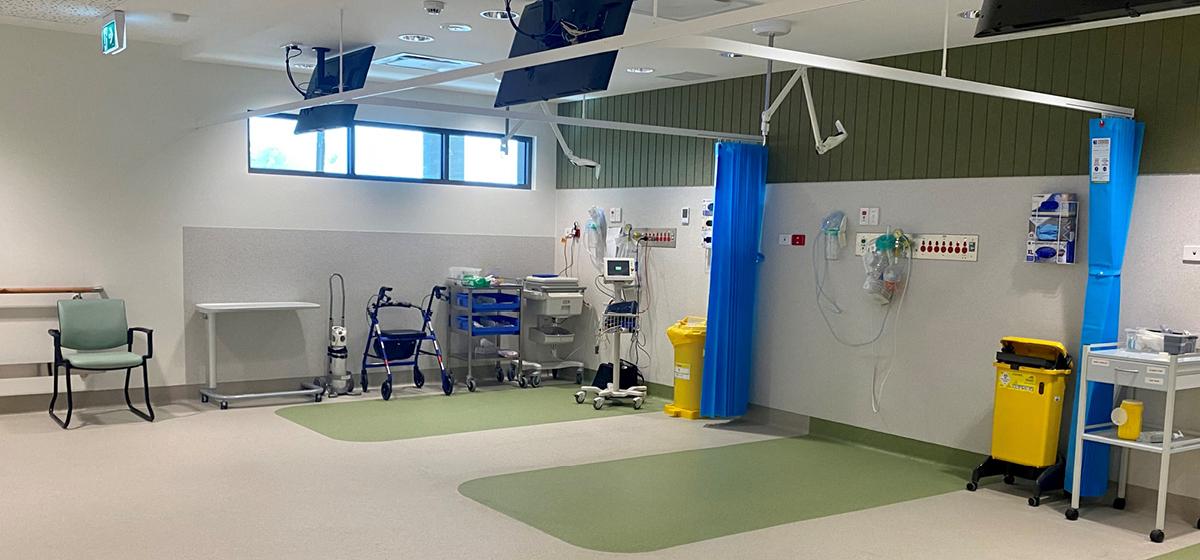 A diagnostics area of Ballrat Base Hospital. There are two green mats, a chair and medical equipment.