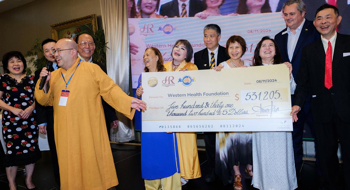 Some Vietnamese community members grinning broadly while holding large cheque with the numbers $531,205