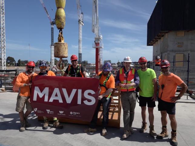 A group of construction workers at the site of the new Footscray Hospital, holding a large red sign that says 'Mavis'