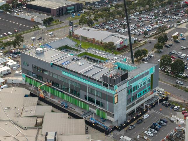 Close aerial view of cranes installing a module on a hospital