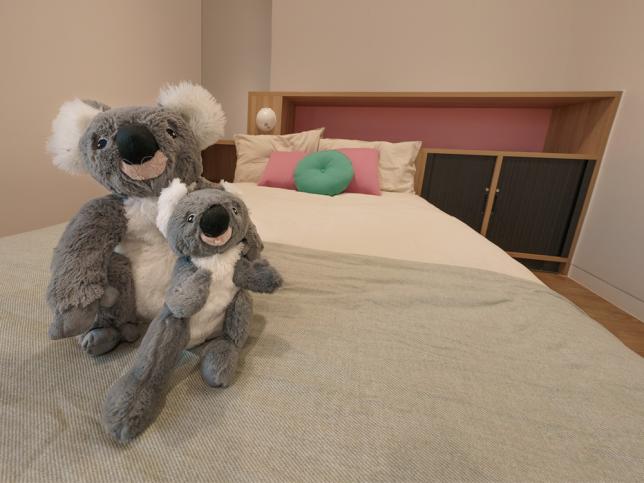 A bed with two toy koalas sitting at the end