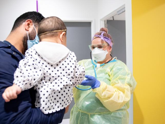 Photo of a nurse assessing a very young child being held by their father at Sunshine Hospital children's emergency department.