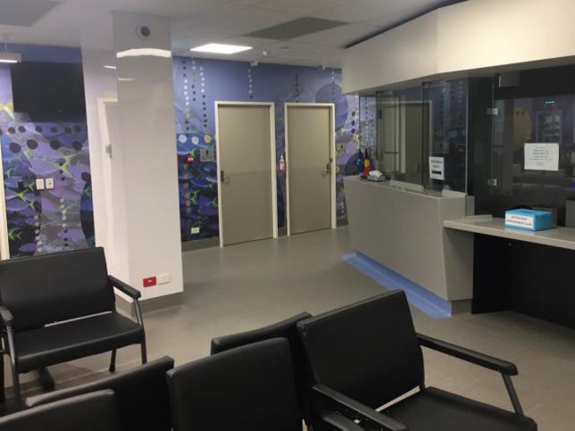 Waiting room with chairs and a reception at the Moorabbin Hospital. There is an Aboriginal artwork mural on a wall.