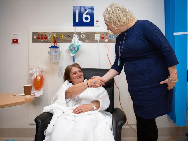 A woman who is standing up shakes hands with a patient who is sitting down at Broadmeadows Hospital.