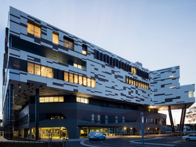 External view of the entrance to Werribee Mercy Hospital, at dusk with lights visible through the windows