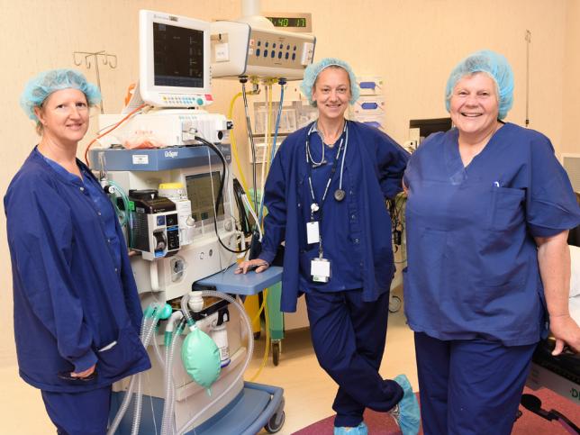 Three nurses in scrubs standing together and smiling