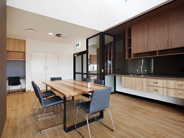 A dining area with a wooden dining table and a benchtop with a sink