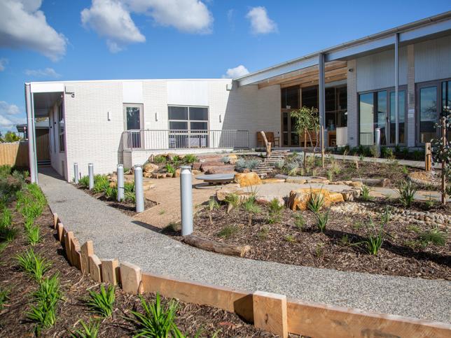 A grey path lined with plants leads to the white Statewide Child and Family Centre