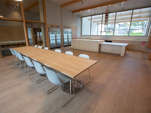 Long wooden table with white chairs in a large dining space