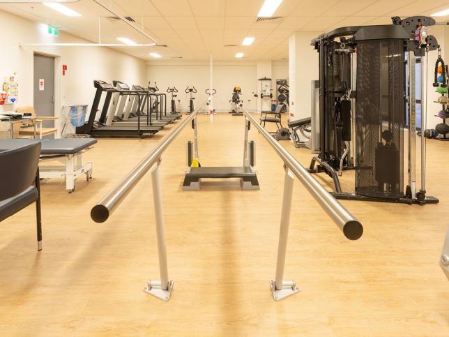 A timber-floored gym area, with treadmills, weight machines and parallel bars