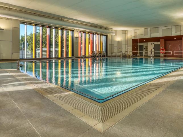 A hydrotherapy pool, bathed in sunlight that streams through the large window on the wall behind the pool