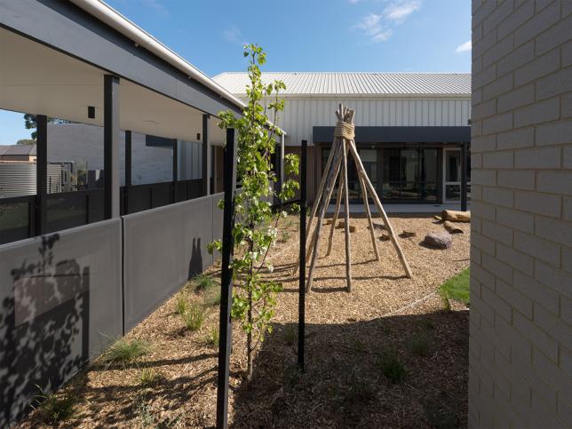 A tanbarked play area with shrubs and grass