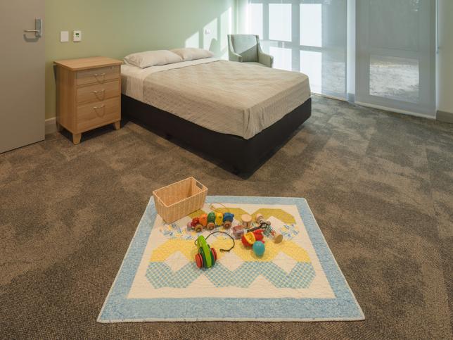 Bedroom with colourful rug and toys.