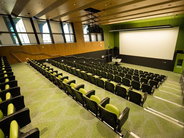 A lecture theatre with green carpet 