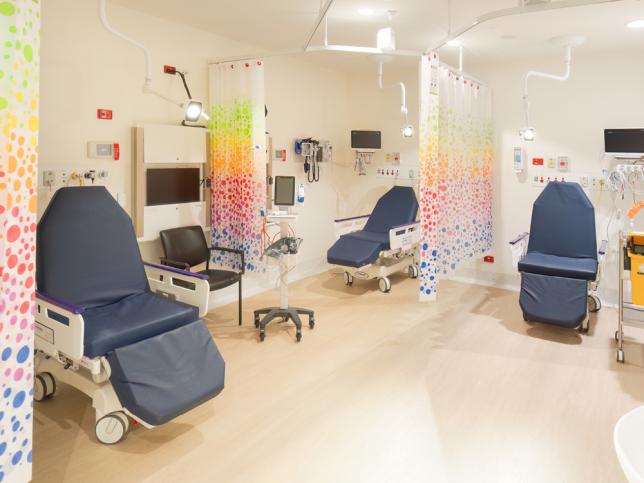 A calm looking space with pale wood floors and colourful curtains