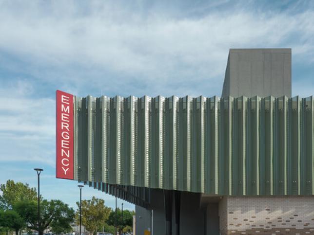 A red emergency sign contrasts with the green roofing and blue sky