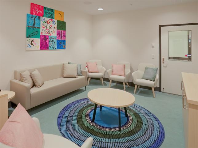 A cosy and welcoming-looking room dotted with sofas, chairs and a coffee table and rug