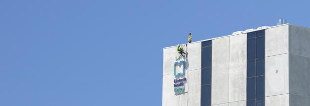 Abseilers instal signage at the Casey Hospital 