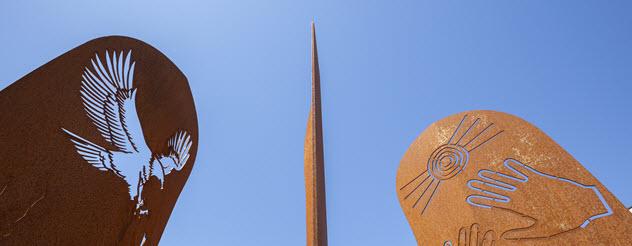 Detail of a fire pit in the grounds of the Ballarat and Aboriginal District Co-operative Medical and Regional Health Hub, showing rust-coloured sculptures against a blue sky