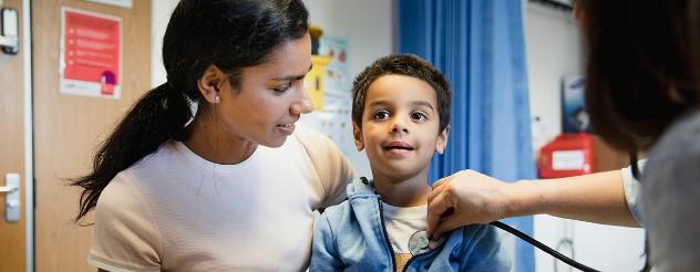 Child getting heart rate check by doctor while sitting beside mother