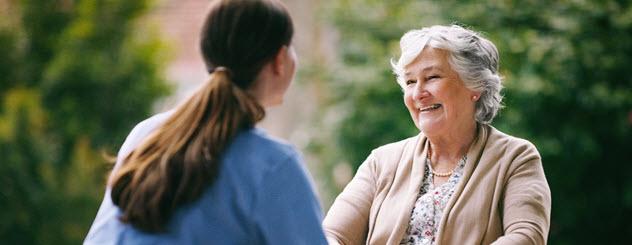 A nurse speaks to an elderly woman in a wheelchair