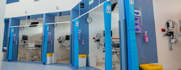 The interior of the Monash emergency department showing four cubicles in a row with blue walls and blue curtains