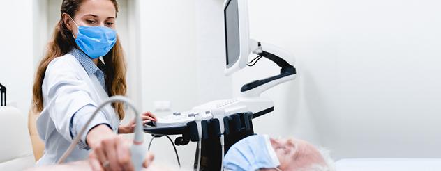 Doctor wearing mask holds a piece of medical equipment over a patient