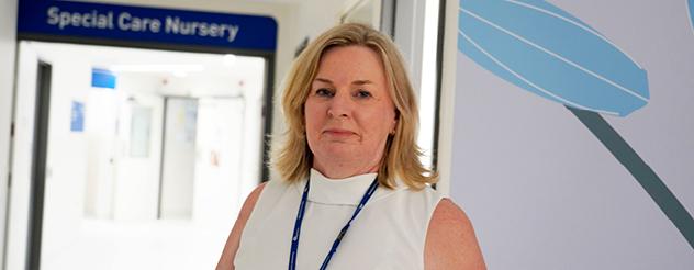 Carmel Brophy, Senior Midwife at GVH Shepparton Hospital. She is smiling at the camera. She has blonde hair to her shoulders. She is wearing a white sleeveless top and a blue lanyard.