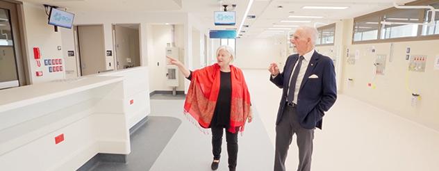 A woman wearing a red shawl is showing a man in a suit around the Wonthaggi Hospital