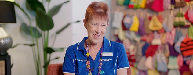 Women with short red hair and blue polo shirt smiling at the camera