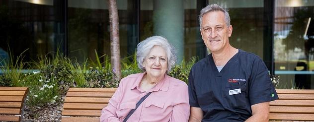 An elderly patient and a staff member sitting on a bench at the Victorian Heart Hospital