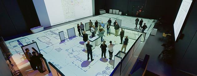 People walking around a large scale floorplan of a room in the Frankston Hospital