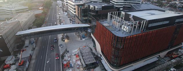 An aerial view of a roofed footbridge connecting two buildings over a road