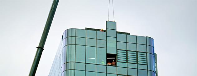 Crane lifting final glass panel onto new Footscray Hospital facade