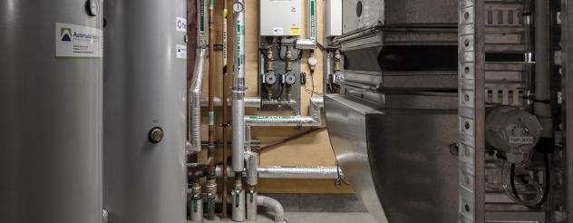 Large medical equipment with pipes and metal canisters in a dark room. 