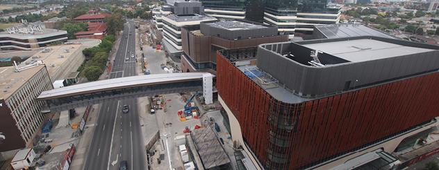 Aerial view showing building with red facade and footbridge stretching across a busy road