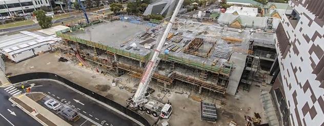 An aerial view of construction on the Werribee Mercy Hospital expansion, with a crane lifting materials